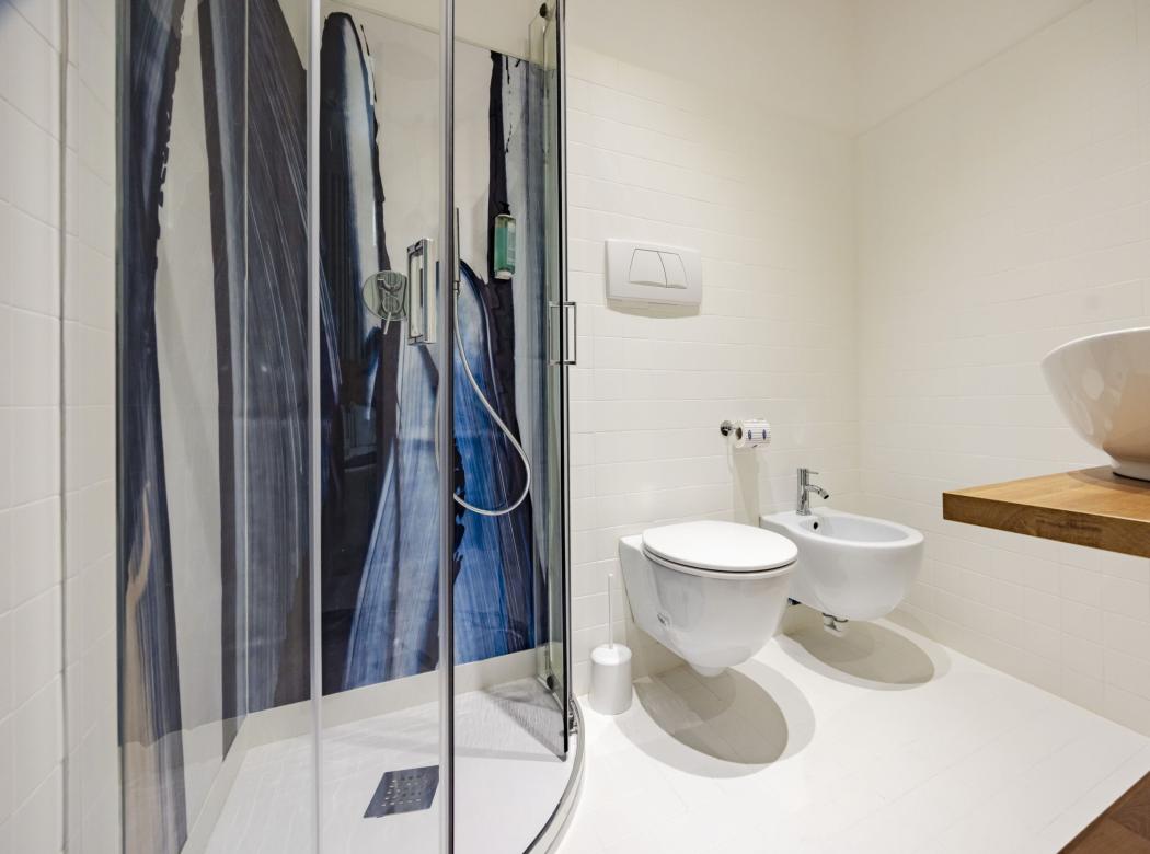 Modern, elegant bathroom with artistic shower and sink on wooden shelf.