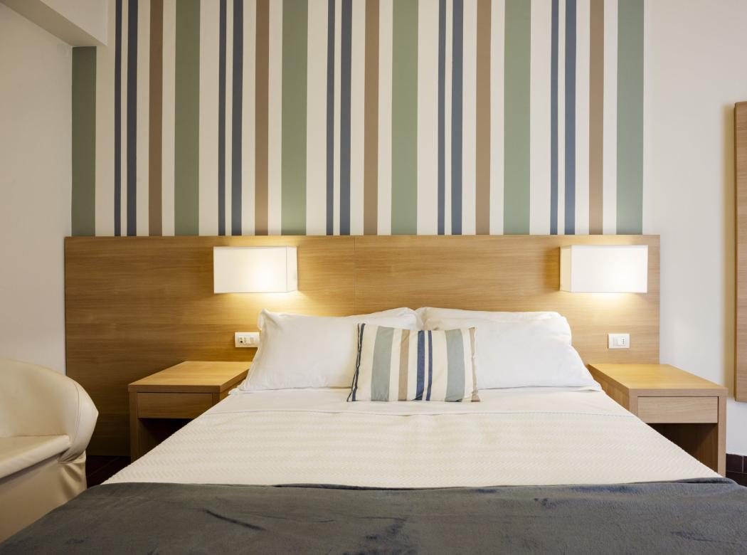 Cozy room with a double bed, warm lights, and colorful striped walls.