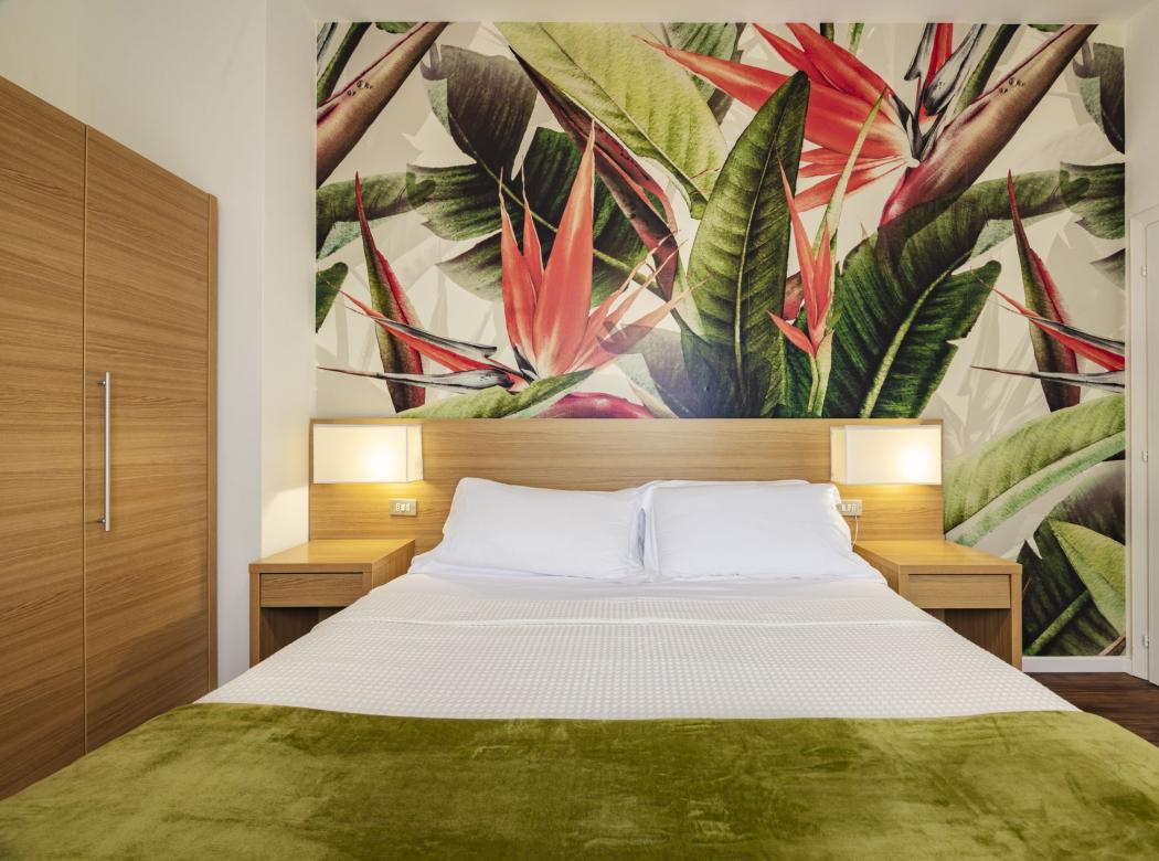 Cozy room with vibrant floral wall and light wood furnishings.