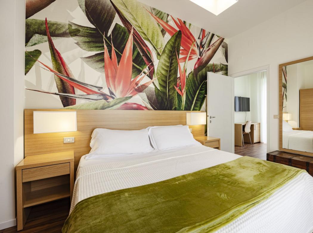 Bright room with tropical wall and green blanket.