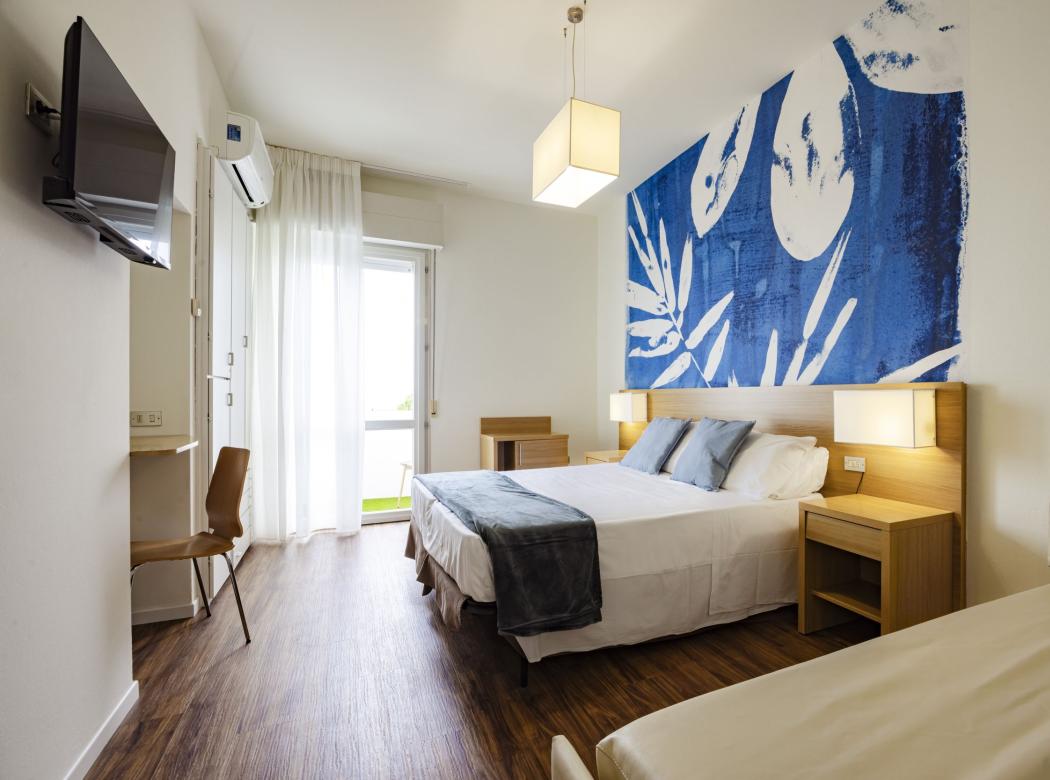 Bright room with blue decor, cozy bed, and balcony view.