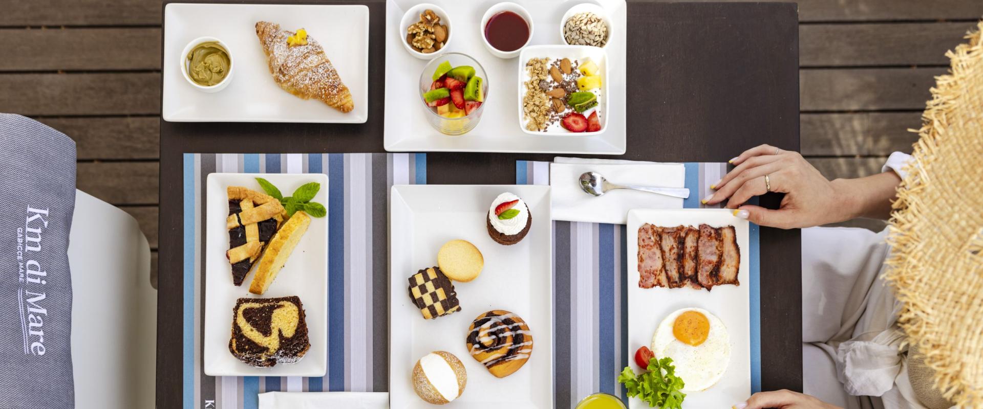 Elegant breakfast with pastries, fruit, eggs, and newspaper on wooden table.
