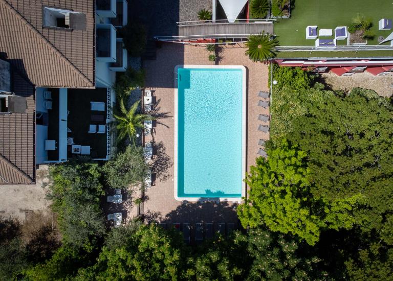 Piscina rettangolare con lettini e ombrelloni, vista dall'alto.